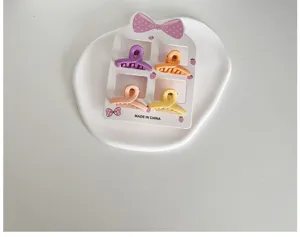 Détail de quatre mini-pinces à cheveux colorées pour filles sur une carte décorée