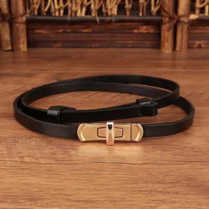 Gedetailleerd overzicht van de slanke zwarte lederen riem met gouden draaisluiting.