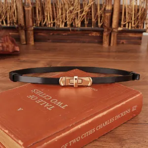 Close-up van de smalle zwarte lederen riem met gouden draaisluiting metalen gesp voor dames.
