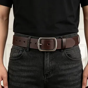Close-up detail of a classic brown leather belt with a silver pin buckle worn on dark jeans