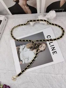Detailed view of women elegant gold metal chain belt with leather weave and pendant accessory.