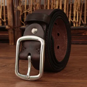 Macro detail of a vintage dark brown genuine leather belt featuring a silver metal buckle