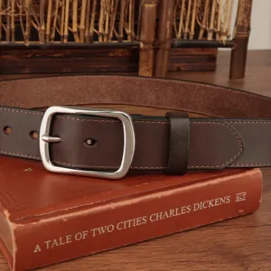 Close-up of vintage brown leather belt with silver pin buckle on a book background.