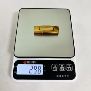Vista dettagliata fibbia per cintura in metallo dorato, chiusura a pressione leggera.