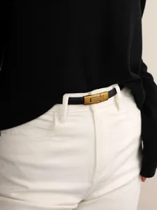 Primo piano di una elegante cintura sottile in pelle nera con chiusura a pressione dorata.
