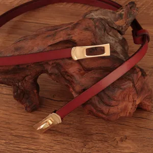 Slanke bordeauxlederen riem met een elegante goudkleurige metalen gesp voor stijlvolle jurken.