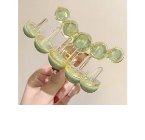 Close-up of a large green and yellow bubble hair claw clip held in hand