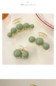 Three sage green minimalist shark clips in various sizes on a clean white surface