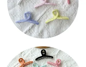 Macro shot of assorted macaron-colored fabric-wrapped hair claw clips on lace fabric