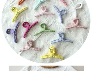 Variety of colorful fabric-wrapped hair claw clips on white textured background
