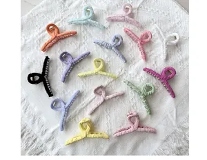 Macro view of various colorful fabric-covered claw clips on a white lace background.