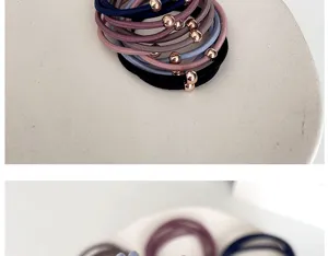 Close-up view of premium elastic hair ties featuring rose gold beads on a white ceramic plate