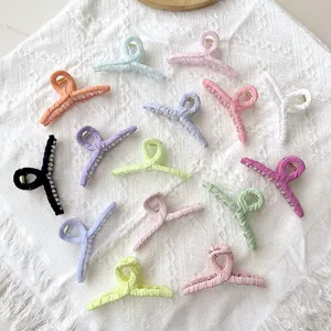Assorted pastel fabric-wrapped hair claw clips arranged on a white textured cloth background