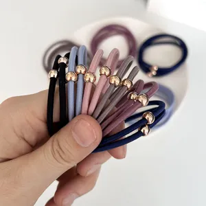 Hand holding assorted high-elastic hair ties with minimalist gold bead decoration