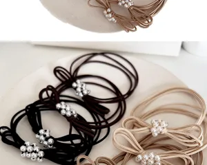 Detailed macro view showing the elegant pearl bow accents on multi-strand hair ties