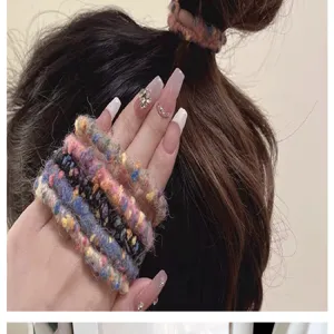 Detailansicht von bunten, bonbonfarbenen gestrickten Woll-Haargummis an Hand und Haar.