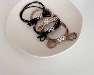 Detailed view showing the elegant pearl bow design of elastic hair ties in black and beige