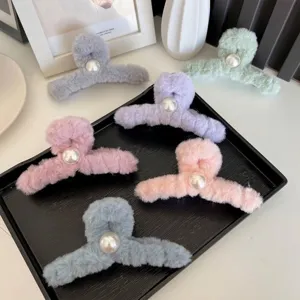 Lot de pinces à cheveux en peluche avec perles de couleurs pastel sur un plateau noir