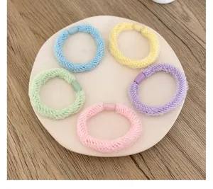 Detail view of five colorful braided elastic hair ties arranged on a white display plate