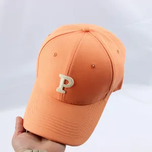 Orange baseball cap detail showing embroidered letter P on crown and curved brim for casual wear.