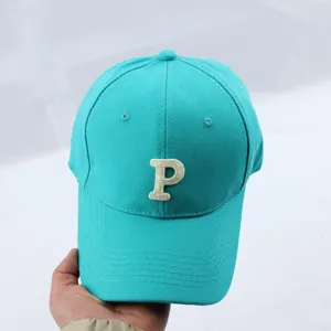 Turquoise baseball cap detail showcasing the front white embroidered letter P and neat stitching.