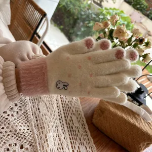 Close-up detail of cute rabbit embroidered knitted winter gloves with plush pink cuffs.