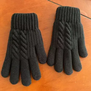 Close-up of black knit gloves with cozy cable pattern and ribbed cuffs for winter warmth.