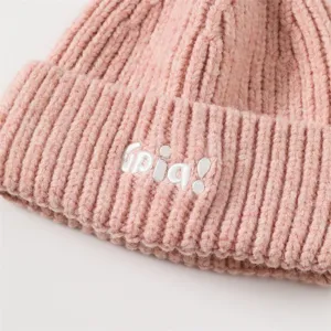 Close-up knit texture and white embroidered letter detail of winter warm pink beanie hat.