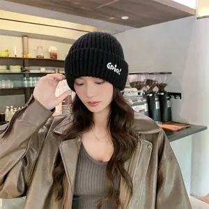 Cozy black knit beanie hat with stylish white letter embroidery for autumn and winter wear.