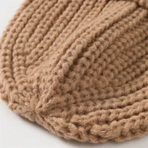 Close-up detail of cozy brown knitted winter beanie showcasing soft wool texture and warmth.