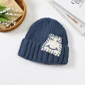 Blaue Winter Strickmütze mit niedlichem Aufnäher, warmer und stylischer Rollrand für Damen.