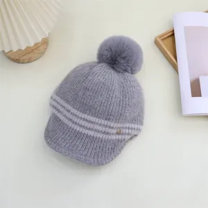 Grey knitted pom pom hat detail, cozy winter ribbed beanie with visor and soft furry pompom.