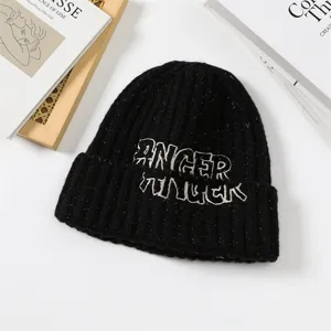 Black knitted beanie hat, thick warm winter cap with embroidered lettering, stylish Korean style.