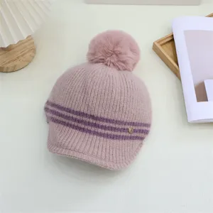 Detailed view of women's pink striped knitted hat with plush pom-pom and cozy winter design.