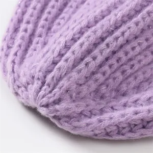 Close-up detail of a stylish purple winter knitted beanie with sparkling silver threads.