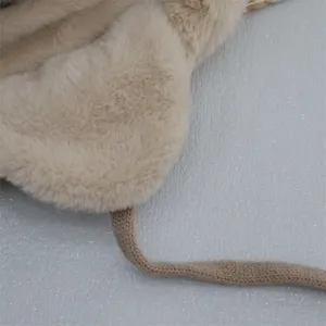 Detail shot of winter plush earflap hat, thick warm beige faux fur with knitted strap.