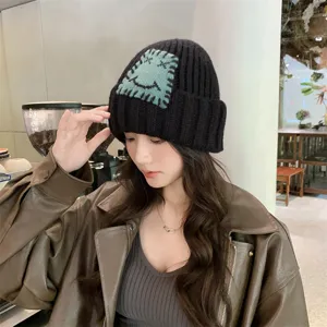 Gemütliche schwarze Strickmütze für Damen mit einem süßen grünen Patch, warme Winter Umschlagmütze.