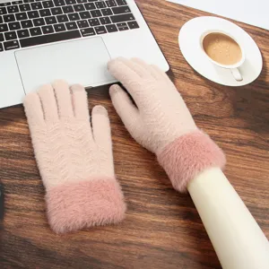 Closeup of women winter warm touchscreen knitted gloves with cozy plush cuffs in stylish pink tone.