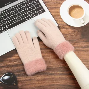 Close-up detail of winter women's touchscreen knitted gloves with warm furry cuffs on wooden desk.