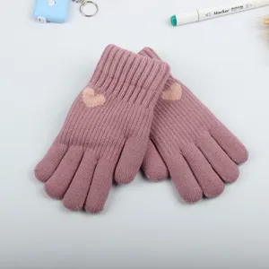 Close-up detail view of cozy pink knitted winter gloves featuring a cute heart pattern.