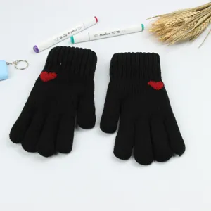 Detailed shot of black knitted winter gloves featuring cute red heart patterns, warm and cozy.