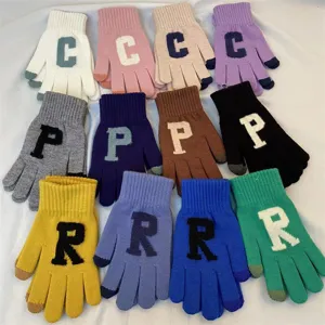 Vue rapprochée détaillée de gants tricotés colorés avec des motifs de lettres pour l'hiver.