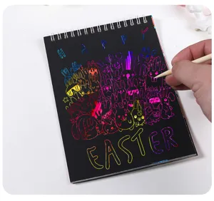Close-up of DIY rainbow scratch art book with Happy Easter bunny design and wood stylus