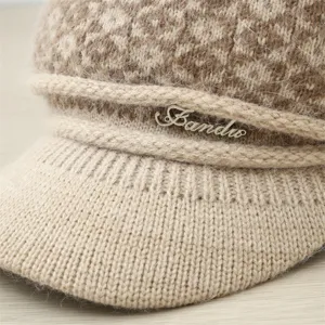 Detailed view of women's warm knitted visor hat with fuzzy pattern and metal logo decor.