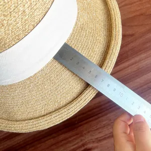 Detailed view of the French straw sun hat brim being measured with a metal ruler for size.