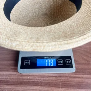 Straw hat weight detail showing 173 grams on digital scale, lightweight summer sun hat.