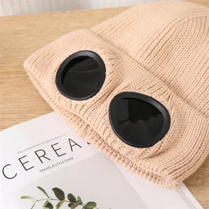 Berretto in maglia beige con dettaglio di lenti a occhiale nere streetwear invernale.