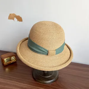 Detail shot of the elegant woven straw hat showcasing its delicate texture and green ribbon bow.