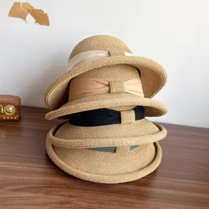 Close-up detail of stacked summer straw sun hats with elegant ribbons and rolled brims.