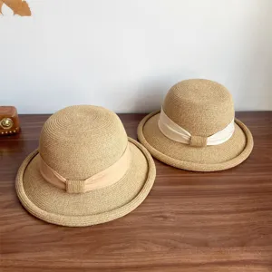 Detail view of French style straw sun hat with elegant ribbon bow and rolled edge for summer.